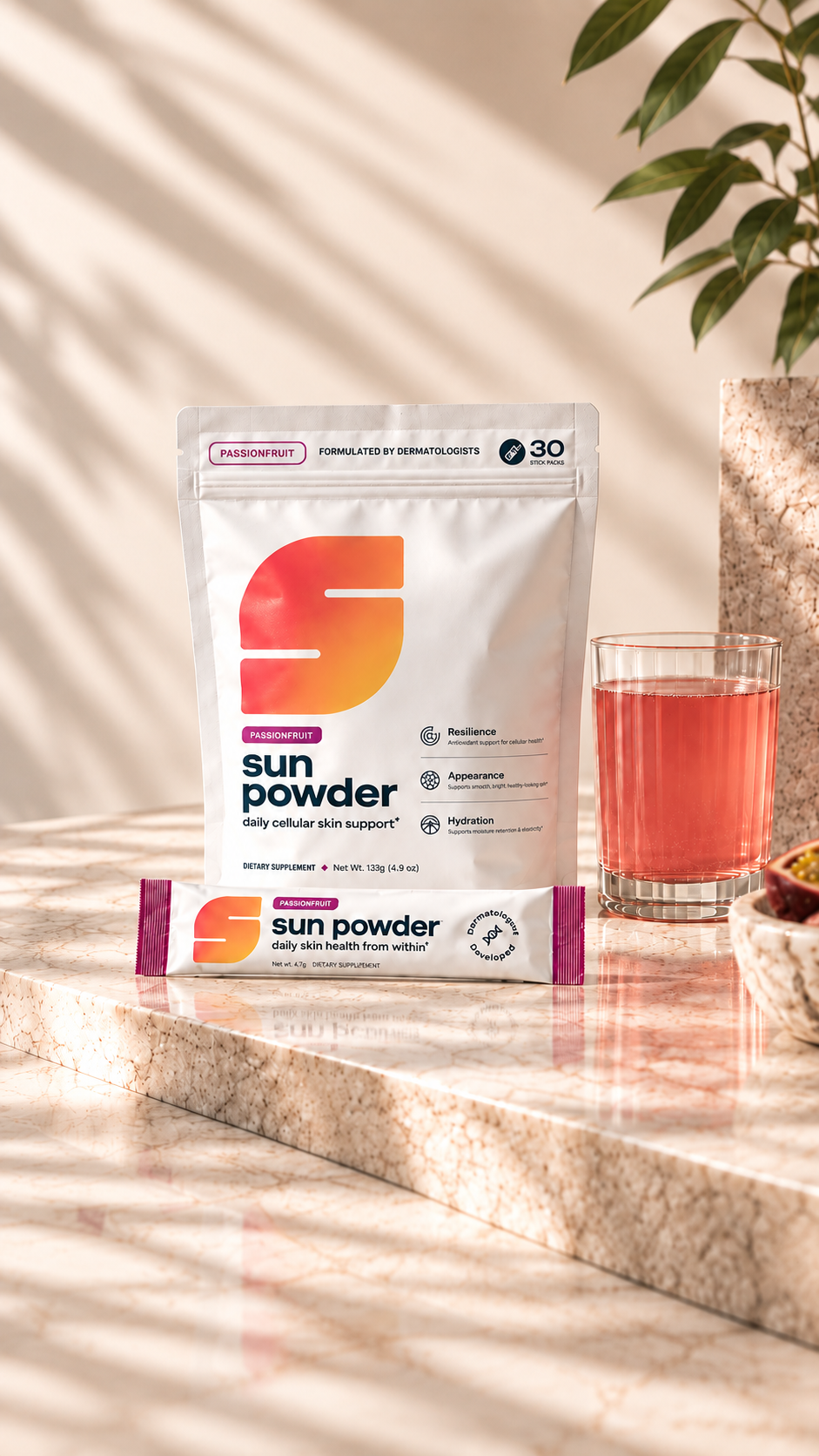 A Sun Powder Passionfruit pouch and stick pack next to a glass of Sun Powder on a marble ledge